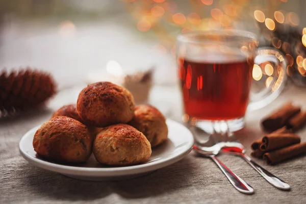 Siyah çay, tarçın, Noel ışıkları ve el ile süslenmiş ile üç küçük lor ve yulaf ezmesi buns mum arka planda yapılan.