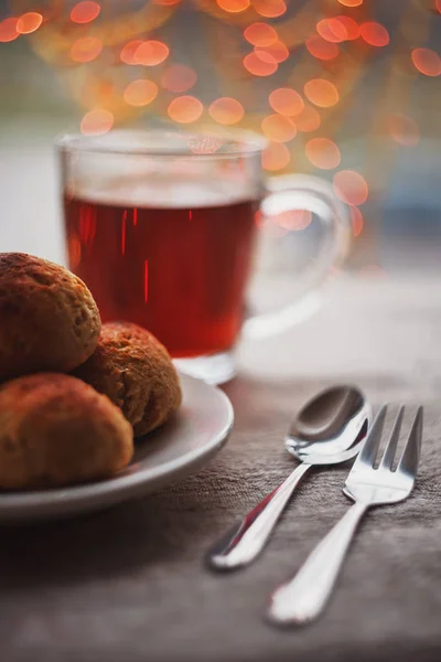 Siyah çay, tarçın, Noel ışıkları ve el ile süslenmiş ile üç küçük lor ve yulaf ezmesi buns mum arka planda yapılan.
