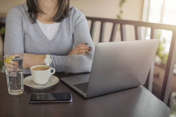 Eğitim mola genç kızla kahve içme ve restoranda, dizüstü kullanarak gri kazak. Kahve içme ve internet hakkında bilgi arıyorum.