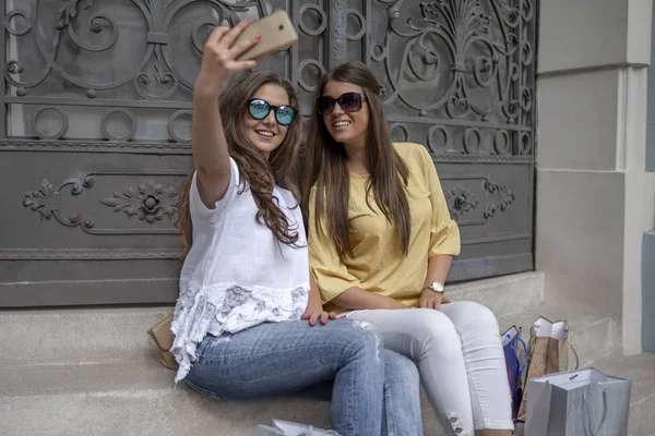 Дві Привабливі Усміхнені Дівчата Сумками Сидять Сонячний День Після Покупки — стокове фото