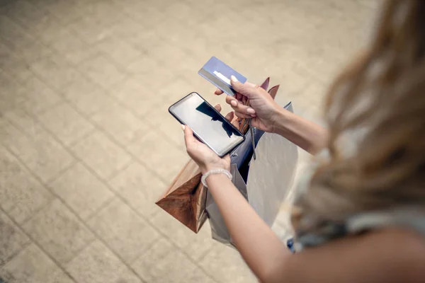 Kız alışveriş. Sarışın kadın alışveriş torbaları, kredi kartı ve telefon ile. Kredi kartı ve cep telefonu holding eller. Online alışveriş. Alışveriş, yaşam kavramı.