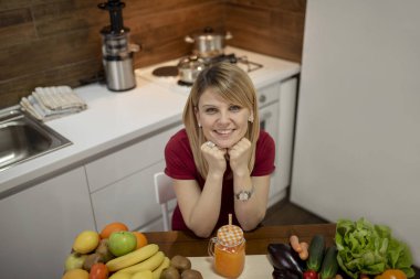 Mutfakta içme güler yüzlü genç bir kadın. Mutfakta genç kadın portresi kapatın. Sağlıklı gıda - sebze salatası. Diyet. Diyet kavramı. Sağlıklı bir yaşam tarzı. Evde yemek. Yemek hazırlamak