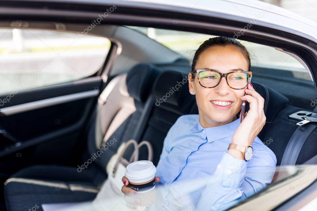 Business woman drinking coffee in the back seat of the car. Beau