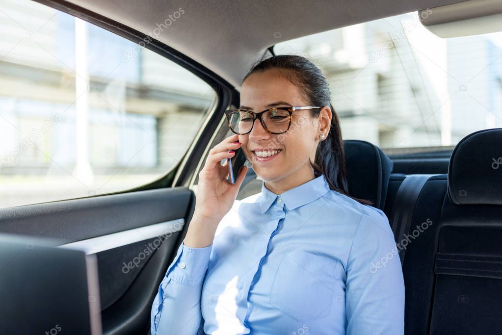 Portrait of businesswoman talking on the phone in the back seat 