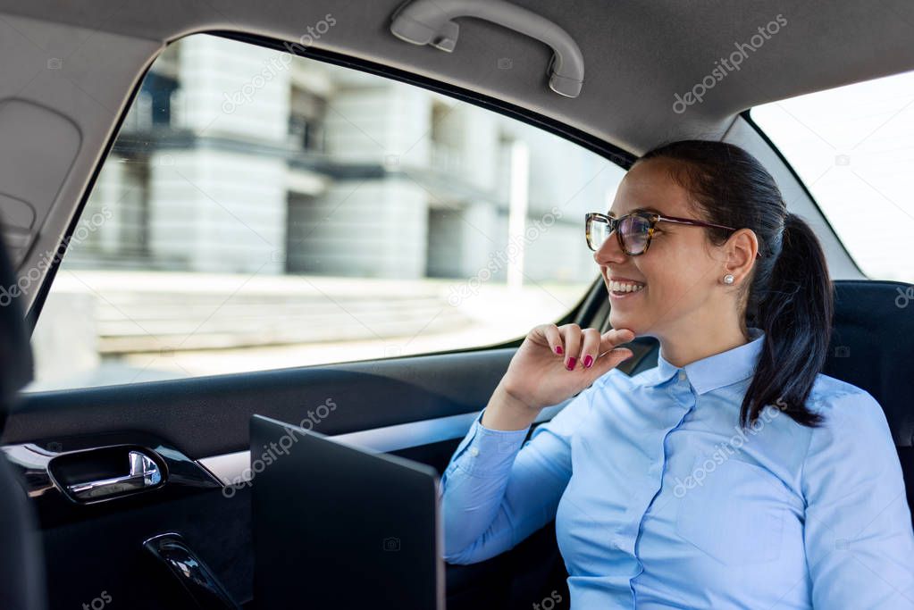 Attractive business woman in the back seat of the car.