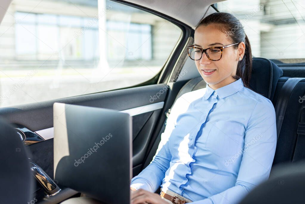 Portrait of business woman sitting in the car. Business woman with laptop. Attractive business woman in the car. Business and lifestyle concept.