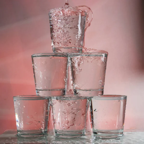 Six glasses stacked by a tower on a multi-colored background