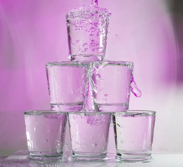 Six glasses stacked by a tower on a multi-colored background