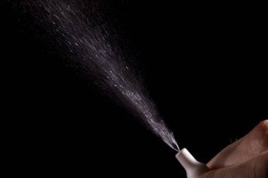 Siyah bir arka plan üzerinde havada burun için sprey püskürtülür