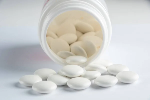 White round tablets covered with a cover are scattered from a plastic can with them