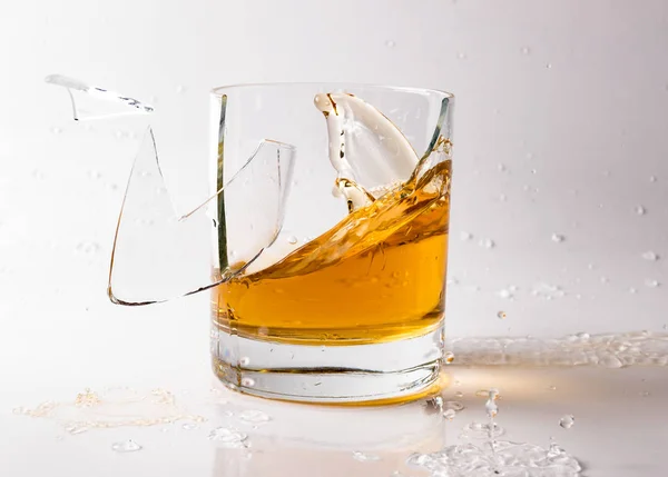 A shattering glass of brandy or brandy. Shards of glass and splashes of drink