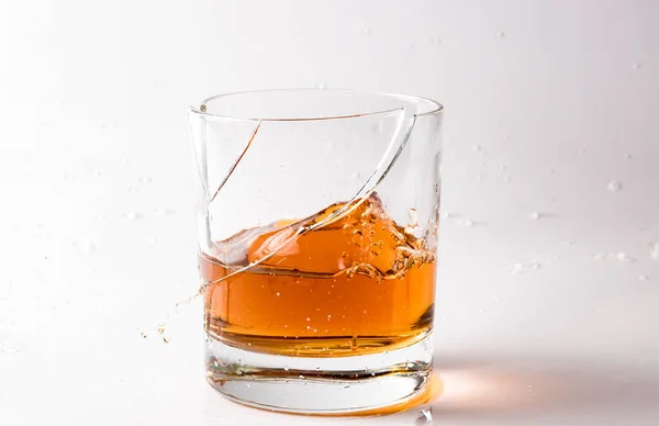 A shattering glass of brandy or brandy. Shards of glass and splashes of drink