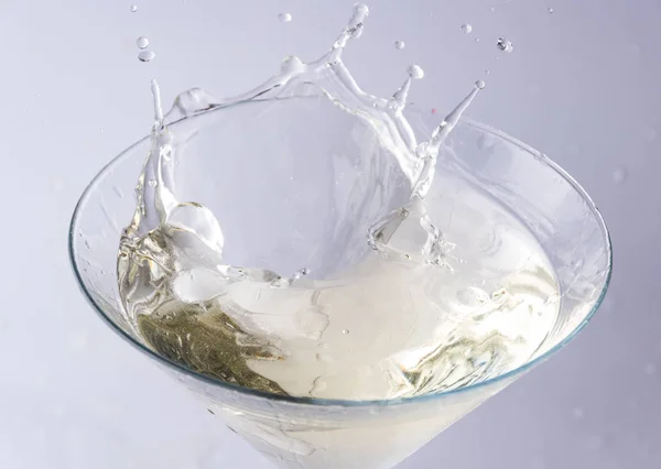 一个装有苦艾酒的杯子和一块冰扔在它身上 饮料的飞溅和飞溅 — 图库照片