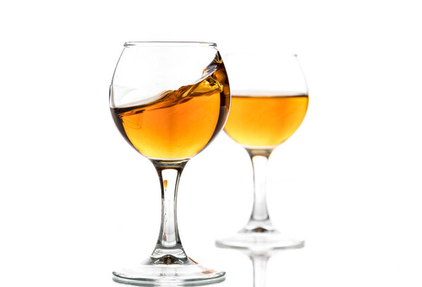 A round glass with brandy and a splash of drink inside