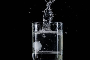 Bounce ve su siyah bir arka plan ile şeffaf cam içine atılmış buz parçası üzerinden sıçrama