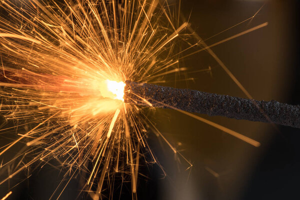 Burning sparkler close up on a black background, a lot of sparks