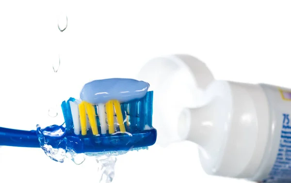 点眼薬と水の水しぶき 白地に青い歯ブラシに歯磨き粉 — ストック写真