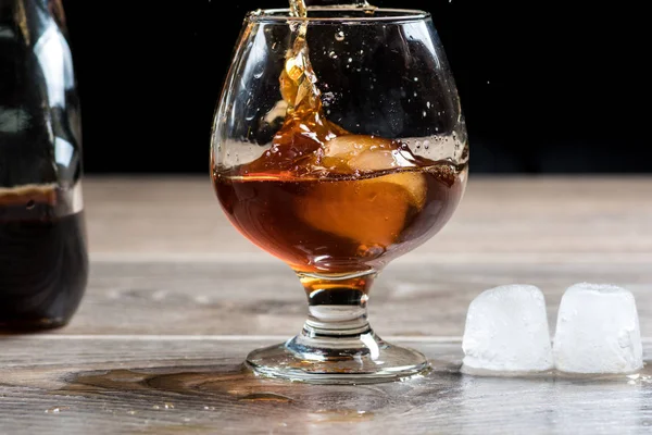 Glass of whiskey and splashing from falling ice