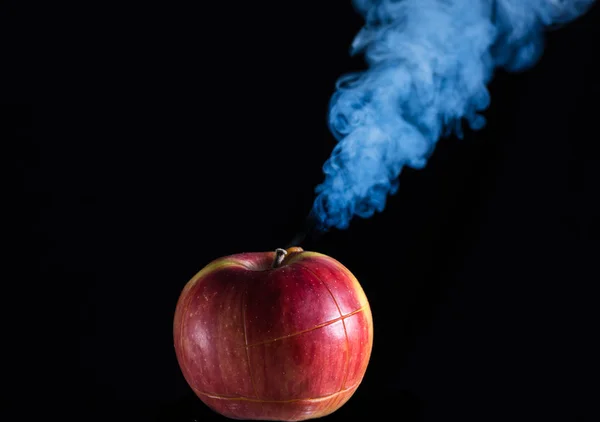 Red apple with cuts on a black background is smoking