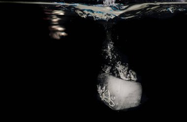 Siyah bir zemin üzerine su içine atılmış buz topakları