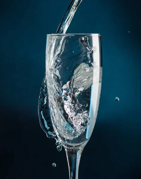 Бризки Келиху Шампанського Проти Падаючої Води Темно Синьому Фоні — стокове фото