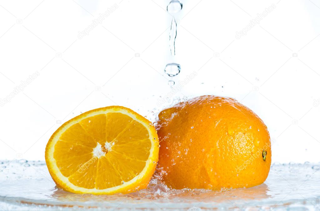 Orange and grapefruit in a spray of water on a white background