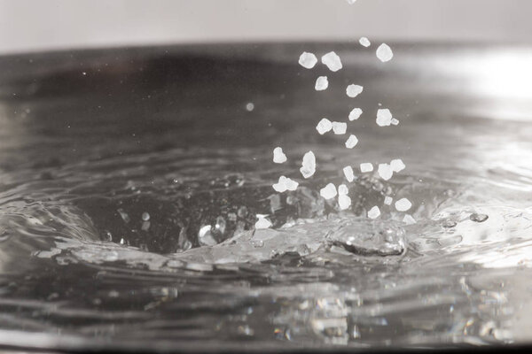 Add salt to boiling water in a metal pan close-up