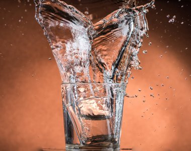 turuncu kahverengi arka planda buzla bir bardak viski içinde sıçrama