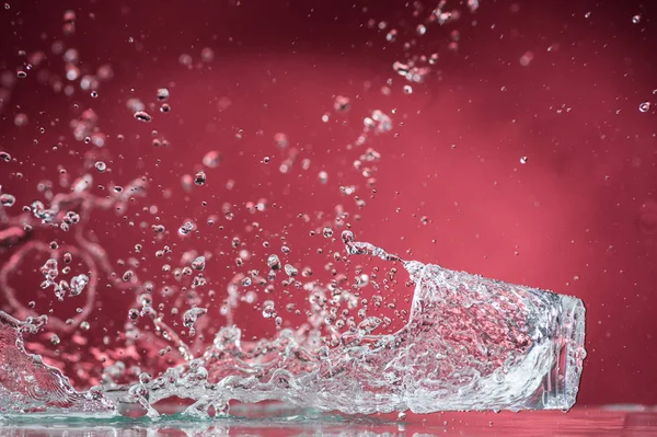 Caindo Pequenos Copos Derramando Água Fundo Vermelho — Fotografia de Stock