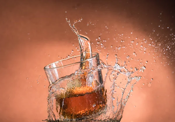 Salpicadura Vaso Whisky Con Hielo Sobre Fondo Marrón Anaranjado —  Fotos de Stock