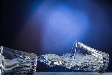 Düşen ve sıvı mavi degrade arka plan üzerinde dökülmesini ile cam atlama