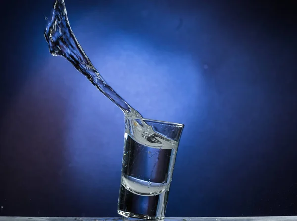 Caindo Saltando Vidro Com Derramamento Líquido Fundo Gradiente Azul — Fotografia de Stock