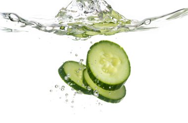 Beyaz bir arka plan üzerinde suya atılan salatalık dilimleri