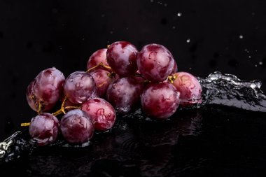 Su spreyi beyaz ve siyah arka plan üzerinde bir yansıması ile üzüm Mor koyu yakın çekim