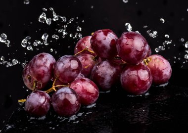 Su spreyi beyaz ve siyah arka plan üzerinde bir yansıması ile üzüm Mor koyu yakın çekim