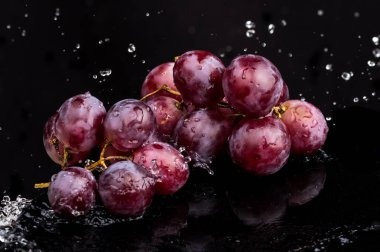 Su spreyi beyaz ve siyah arka plan üzerinde bir yansıması ile üzüm Mor koyu yakın çekim