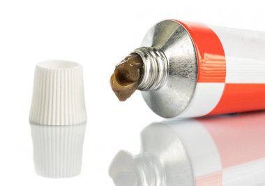 dış kullanım için merhem kapağına yakın, beyaz bir arka plan üzerinde bir tüp biraz sıkılmış