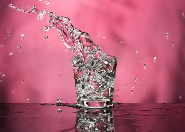 Glass with vodka and a big splash on a colored background