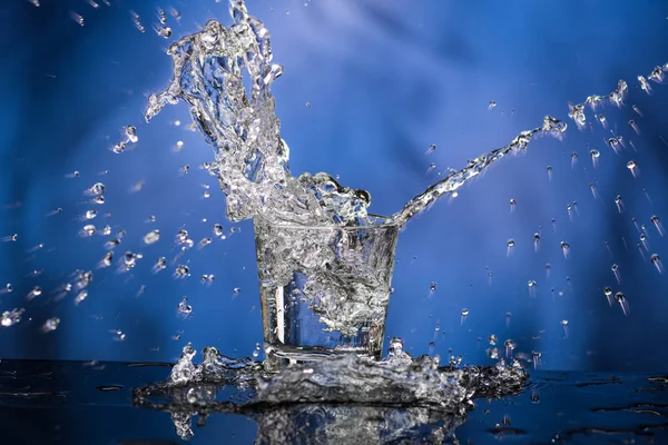 Glass with vodka and a big splash on a colored background