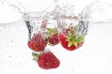 olgun kırmızı çilek atılır ve köpüklü suya düştü, birçok kabarcıklar