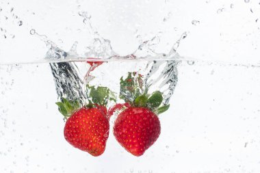 olgun kırmızı çilek atılır ve köpüklü suya düştü, birçok kabarcıklar