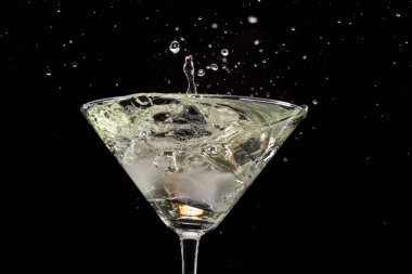 siyah bir arka plan ve yangın üzerinde zeytin ve buz ile martini cam