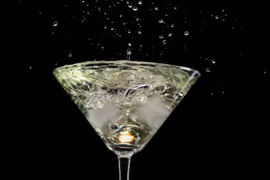 siyah bir arka plan ve yangın üzerinde zeytin ve buz ile martini cam