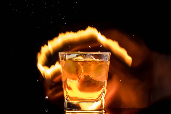 glass with whiskey and falling ice, double wall, splashes and drops