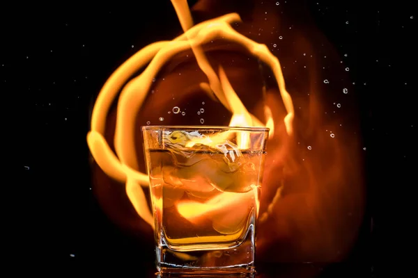 glass with whiskey and falling ice, double wall, splashes and drops