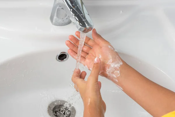 washing hands with soap on a white sink background, male hand or children\'s hands