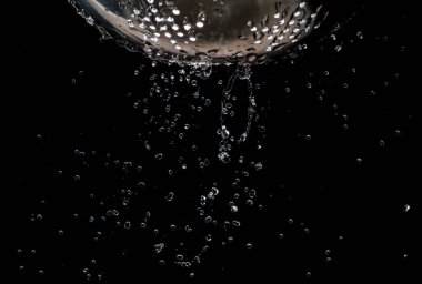 Karanlık bir arka plan üzerinde bir kevgir delikleri ile akış ve su damlaları