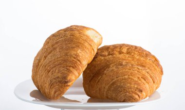 Beyaz arka planda beyaz bir tabakta iki kruvasan.