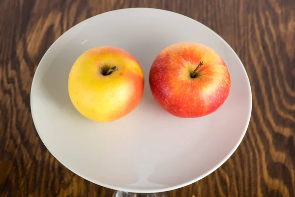red and yellow apple on a white plate on a white background