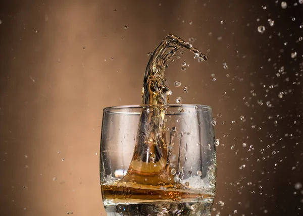 Fallendes Glas Mit Whiskey Und Spray Auf Braunem Hintergrund — Stockfoto